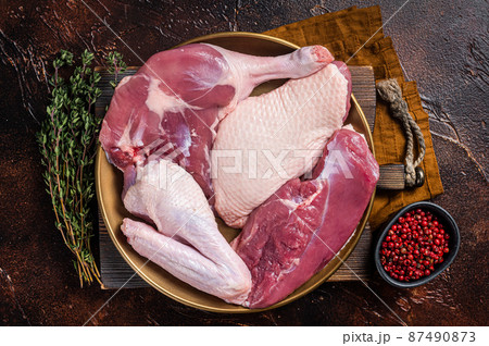 Fresh duck meat parts, raw breast steak, legs, wings in a plate with herbs. Dark background. Top view Fresh duck meat parts, raw breast steak, legs, wings in a plate with herbs. Dark background. Top view 87490873