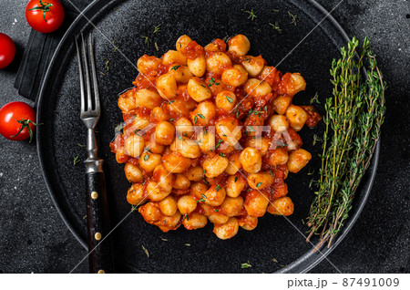 Portion of Italian Gnocchi potato pasta with tomato sauce. Black background. Top view Portion of Italian Gnocchi potato pasta with tomato sauce. Black background. Top view 87491009