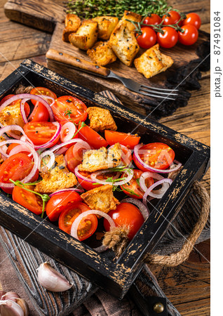 Traditional Italian Panzanella salad with tomatoes, onion and bread Croutons in wooden tray. Wooden background. Top view 87491084