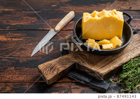 Parmesan hard cheese piece in a pan. Dark Wooden background. Top view. Copy space Parmesan hard cheese piece in a pan. Dark Wooden background. Top view. Copy space 87491143