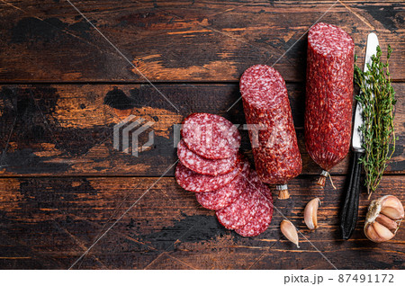 Sliced salami cured sausage on kitchen table. Wooden background. Top view. Copy space 87491172
