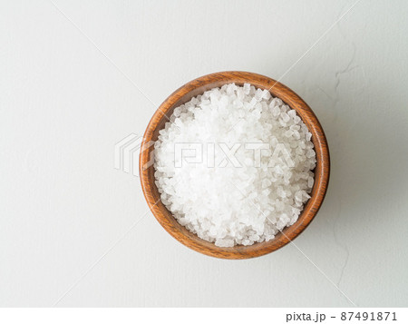 Wooden bowl with large sea salt on gray stone table. Top view, close up 87491871