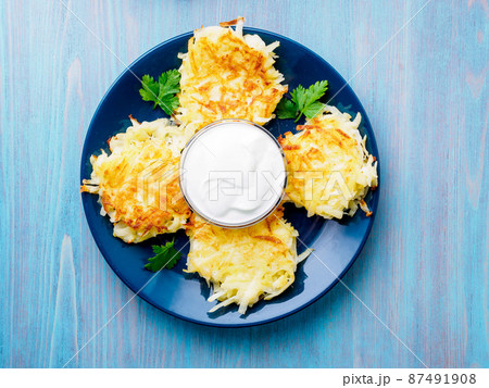 Crispy hashed browned potatoes on blue background, top view. 87491908
