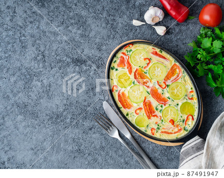 Scrambled eggs with mix of colorful vegetables. Beautiful appetizing dinner. Top view, copy space, dark stone table. 87491947