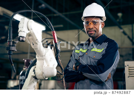 African American factory worker working with adept robotic arm African American factory worker working with adept robotic arm 87492887