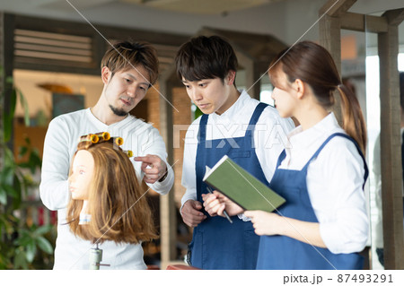 パーマの練習をする若いスタッフ 87493291