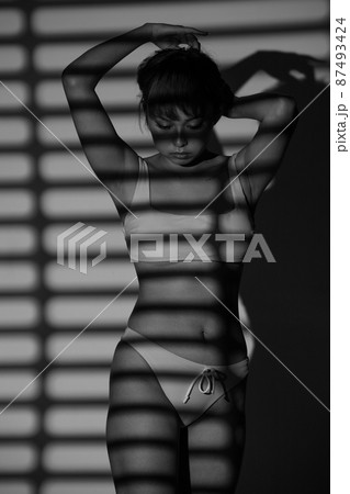 Half body Asian Woman 20s wear Bikini stay in shade of shadow from chick window curtain 87493424