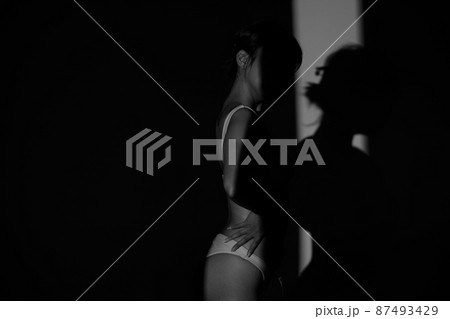 Half body Asian Woman 20s wear Bikini stay in shade of shadow from sunset window curtain Half body Asian Woman 20s wear Bikini stay in shade of shadow from sunset window curtain 87493429