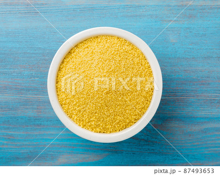 White bowl with raw couscous on blue wooden background, top view. Traditional Moroccan food 87493653