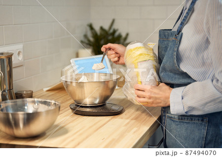 Faceless woman cooking and baking dough on kitchen table at home, 87494070