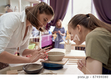 Workshop about training in pottery, one female teaches another Workshop about training in pottery, one female teaches another 87494080