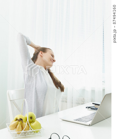 Woman stretches her arms, kneads her back from fatigue. Long sitting at computer, muscle cramps. 87494160