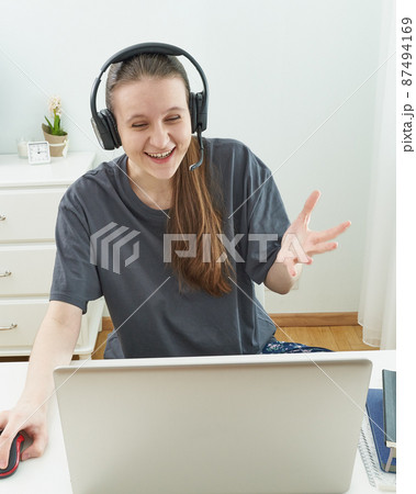Girl with headphones looks at information on computer with surprise. 87494169