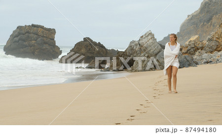 Walk along a sandy beach at the Ocean - Young woman on summer holiday 87494180