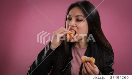 Young woman eats a freshly baked croissant 87494260