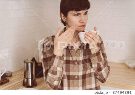 COVID-19 causes loss of smell. Woman sniffing smell of coffee from cup while preparing drink 87494891