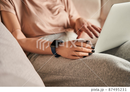 Woman with prosthesis limb sitting at the sofa and using laptop while woking or relaxing at home 87495231
