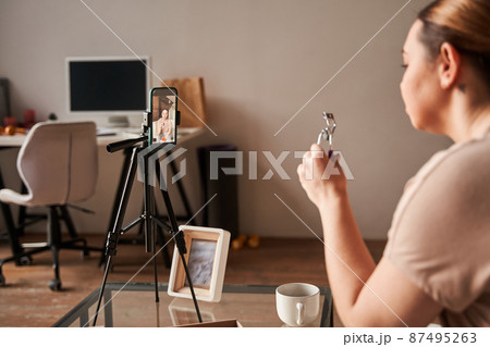 Caucasian blogger talking to camera and showing lushes curler while recording blog about makeup Caucasian blogger talking to camera and showing lushes curler while recording blog about makeup 87495263