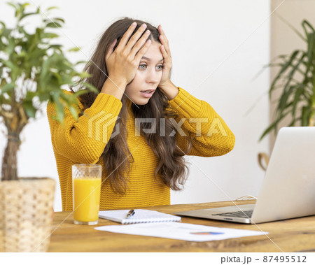 Girl surprising, upset, horror on face. Beautiful young woman working on laptop 87495512