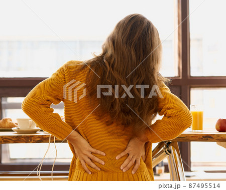 Back view of faceless young woman touching back feeling backache, discomfort 87495514