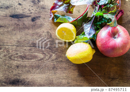 Top view of fresh lemon, apple and beetroot leaves on dark wooden background 87495711