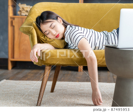 Young Asian girl fell asleep oncouch in front oflaptop. Cute woman is bored, tired or overworked. Young Asian girl fell asleep oncouch in front oflaptop. Cute woman is bored, tired or overworked. 87495953