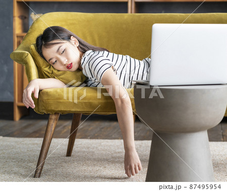 Young Asian girl fell asleep oncouch in front oflaptop. Cute bored woman watching boring movie Young Asian girl fell asleep oncouch in front oflaptop. Cute bored woman watching boring movie 87495954
