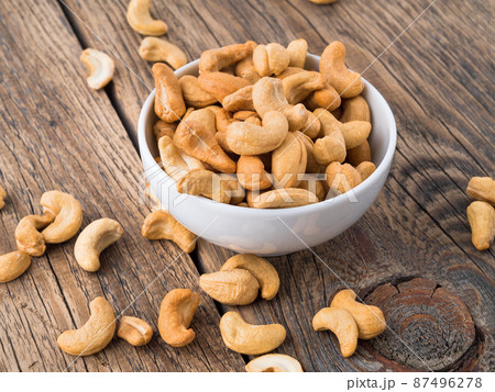 Cashew nuts in white cup on brown wooden background, side view 87496278