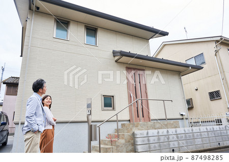 自宅の前に立つ夫婦 87498285