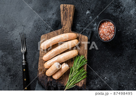 Roasted chicken and turkey sausages on a wooden board. Black background. Top view Roasted chicken and turkey sausages on a wooden board. Black background. Top view 87498495