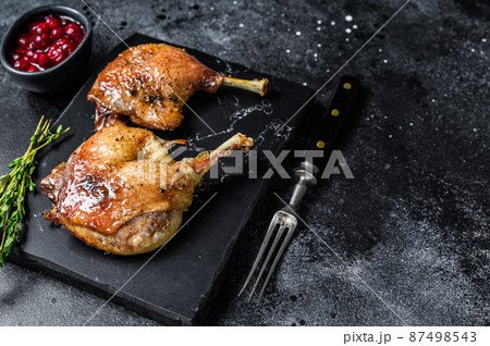 Roasted duck leg confit with cranberrie sauce. Black background. top view. Copy space 87498543