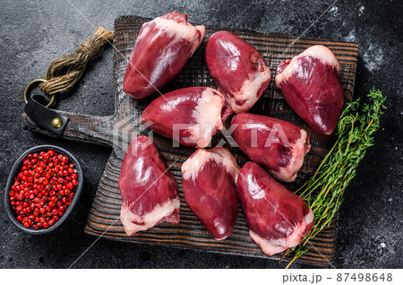 Raw turkey hearts offal with herbs and spices. Black background. Top view 87498648