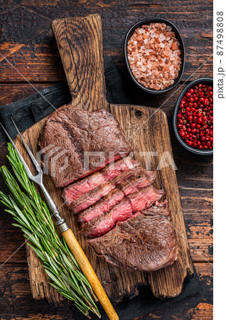 Fried Top Blade or flat iron roast beef meat steaks on wooden board with rosemary. Dark wooden background. Top View 87498808