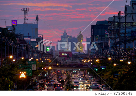 Aerial view of the Giant Golden Buddha in Wat Paknam Phasi Charoen Temple with cars on traffic street road in Phasi Charoen district, Bangkok. Urban town, Thailand. Downtown City. 87500245