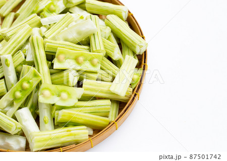 Moringa oleifera cut in pieces in bamboo weave plate on white background. Moringa oleifera cut in pieces in bamboo weave plate on white background. 87501742