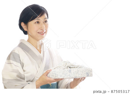 夏の着物を着て風呂敷包み差し出す笑顔の中年女性 お中元のイメージ 夏の着物を着て風呂敷包み差し出す笑顔の中年女性 お中元のイメージ 87505317