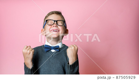 Kid won. Winning success happy boy. School winner. Dynamic image of child with raised hands on pink background. Victory, delight concept. Human facial emotions concept. Trendy colors 87505929