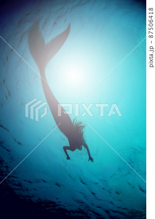 A silhouette shot of a mermaid swimming in solitude in the deep blue sea - ALL design on this image is created from scratch by Yuri Arcurs team of professionals for this particular photo shoot 87506418
