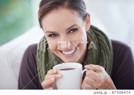 Enjoying the fresh aroma. A young woman smiling happily while holding a cup of coffee - closeup. Enjoying the fresh aroma. A young woman smiling happily while holding a cup of coffee - closeup. 87506474