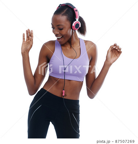 Moving to the beat. A woman in sportswear happily listening to music with her headphones. 87507269
