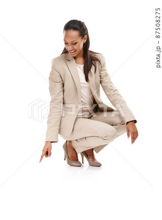 Nowhere to go but up. Full length shot of an attractive young woman in a suit crouching down and pointing towards the ground isolated on white. Nowhere to go but up. Full length shot of an attractive young woman in a suit crouching down and pointing towards the ground isolated on white. 87508275