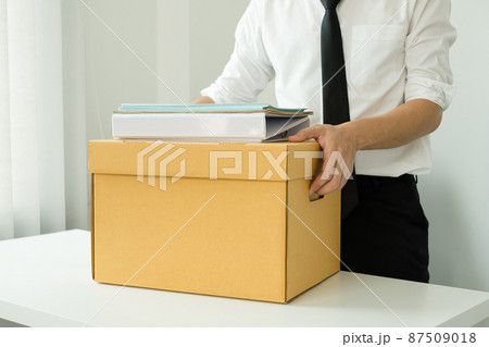 A male office worker is unhappy with being fired from a company packing things into cardboard boxes. The young man was stressed and disappointed by being fired. concept of layoffs and unemployment A male office worker is unhappy with being fired from a company packing things into cardboard boxes. The young man was stressed and disappointed by being fired. concept of layoffs and unemployment 87509018