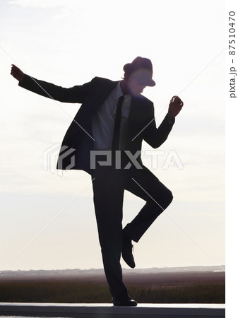 Get up and go. Silhouette image of a young man in a suit dancing against the morning sky. Get up and go. Silhouette image of a young man in a suit dancing against the morning sky. 87510470