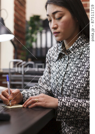 Advertising agency employee writing down client contact information regarding collaboration. Advertising agency employee writing down client contact information regarding collaboration. 87511719
