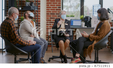Woman therapist giving advice to people at aa group meeting, wearing face mask Woman therapist giving advice to people at aa group meeting, wearing face mask 87511911