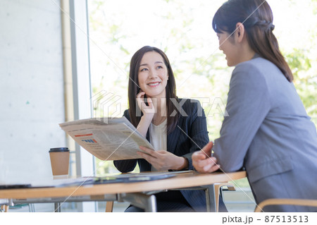 ビジネス 英字新聞を見ながら会話をする2人のビジネスウーマン ビジネス 英字新聞を見ながら会話をする2人のビジネスウーマン 87513513