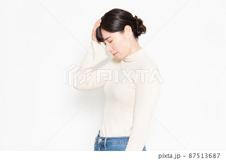白い背景の前に立って頭痛のジェスチャーをする女性 白い背景の前に立って頭痛のジェスチャーをする女性 87513687