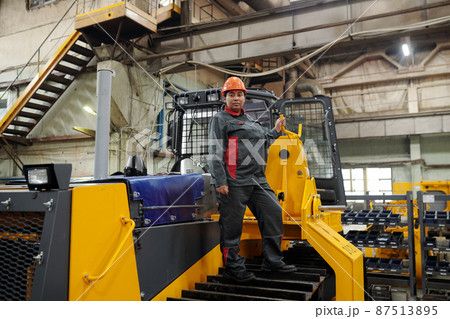 Young confident female worker standing on caterpillar of construction machine Young confident female worker standing on caterpillar of construction machine 87513895