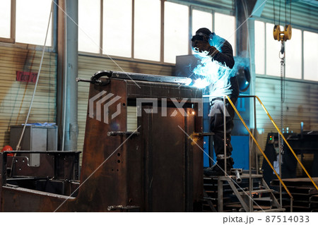 Contemporary worker or welder in protective mask and uniform repairing machine 87514033