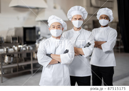 Three well-dressed chefs standing together in the professional kitchen 87515175